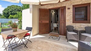 An outdoor patio with a table and chairs, a covered area, and a door leading to an interior space. - Syracuse sea (Arenella)