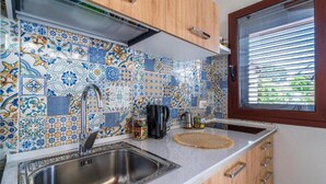 A kitchen with a stainless steel sink, wooden cabinets, and a window with blinds. - Syracuse sea (Arenella)