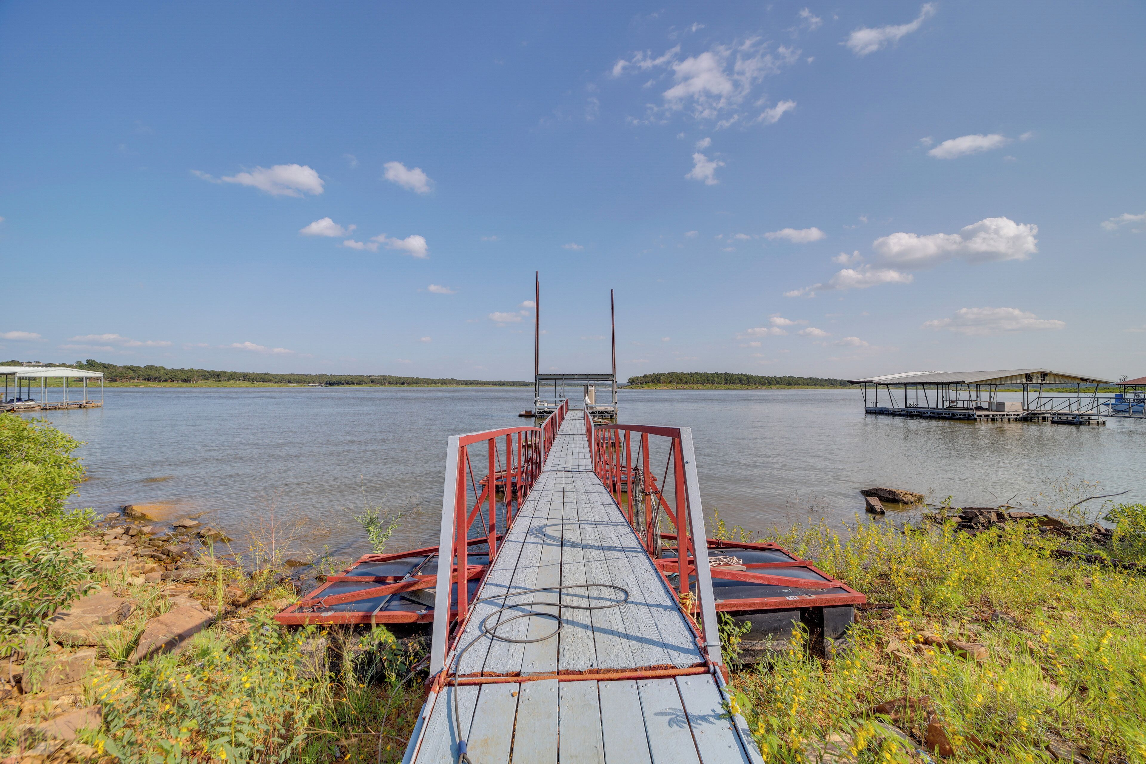 A wooden pier leading into calm water with a clear sky.
