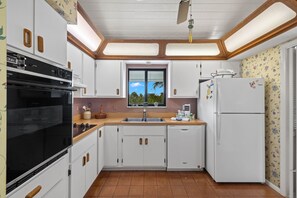 Enjoy a kitchen with oven and refrigerator, offering a view of palm trees.