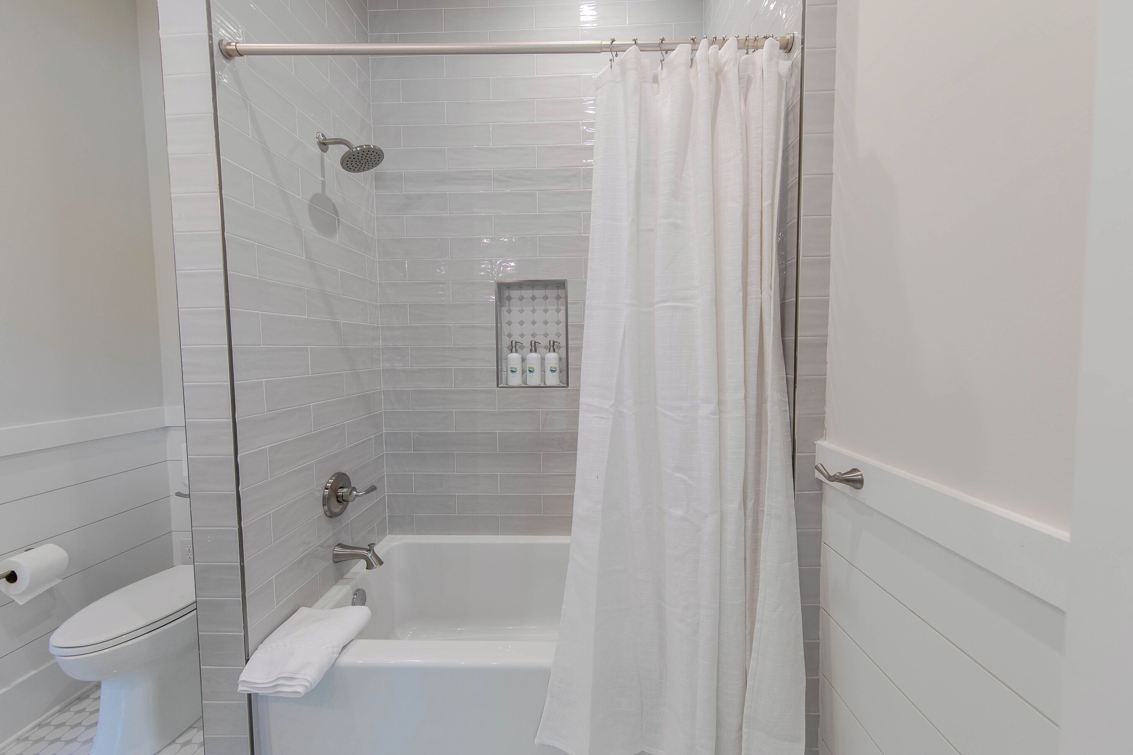 A modern bathroom with a shower, toilet, and bathtub.