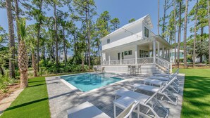 A house with a pool, white outdoor furniture, and a porch. - 30A Brand NEW 4 Bedroom-8 Bikes-LARGE POOL-Turf yard Close to Beach-Golf Cart! (Santa Rosa Beach)