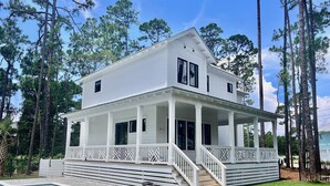 A two-story white house with a covered porch and a swimming pool. - 30A Brand NEW 4 Bedroom-8 Bikes-LARGE POOL-Turf yard Close to Beach-Golf Cart! (Santa Rosa Beach)