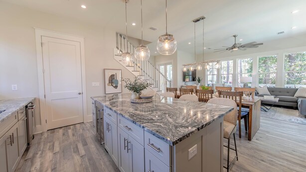 A spacious kitchen with a large island, modern pendant lighting, and a view to the dining area. - 30A Brand NEW 4 Bedroom-8 Bikes-LARGE POOL-Turf yard Close to Beach-Golf Cart! (Santa Rosa Beach)