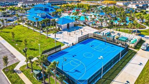 Eine Vogelperspektive zeigt einen luxuriösen Urlaubsort mit mehreren Schwimmbecken, einem großen Tennisplatz und umgebender Bepflanzung.