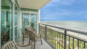 A balcony with a view of the beach, furnished with chairs and a table. - Ocean Front 3 Bedroom, BAY VIEW Resort, 7th Floor, 12 Guests (Myrtle Beach)
