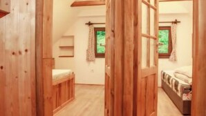 Un interno in legno con un letto a soppalco, una scrivania piccola e una finestra con tende.