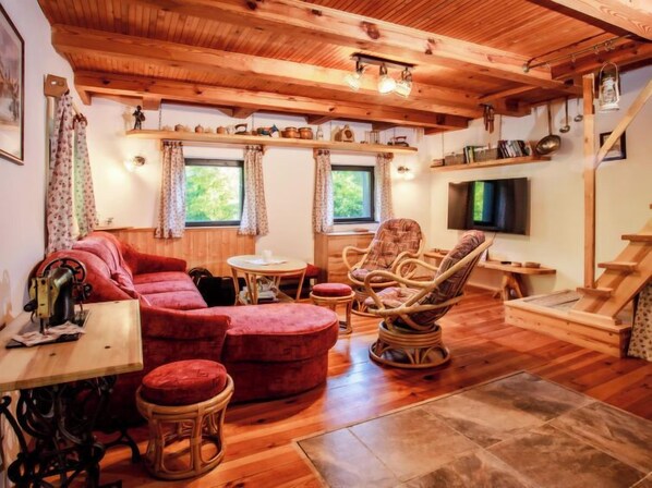 Un salon confortable avec un canapé, des fauteuils, une table et un téléviseur.