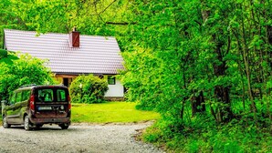 Una casa rustica con un vialetto sterrato che porta a un'auto parcheggiata.