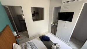 A hotel room with a bed, a small kitchenette, a TV, and a bathroom. - Pretty Studio AC+Wi-Fi 60MB+Kitchen+bathroom (Cancún)
