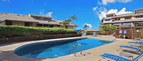 A swimming pool with lounge chairs and a stone wall.
