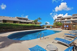 Relax by the resort pool surrounded by palm trees and lounge chairs.