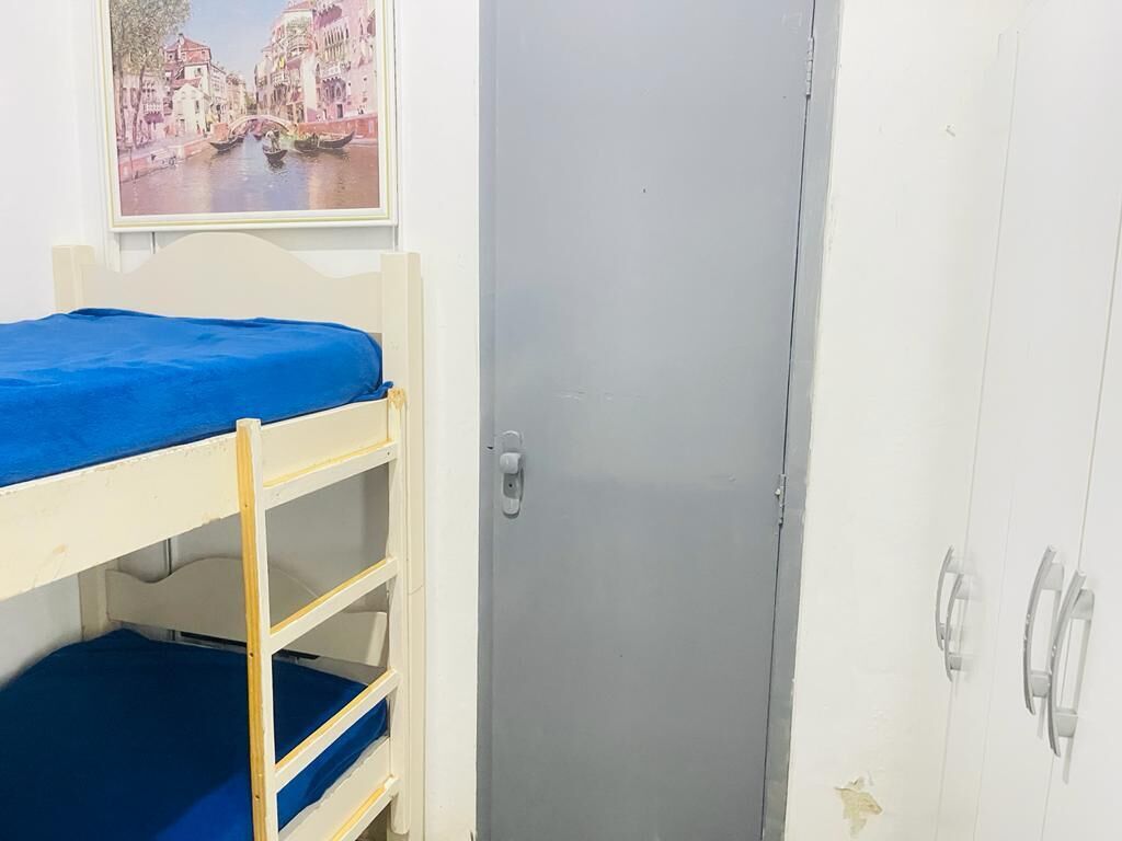 Een stapelbed met een blauwe matras, een grijze deur en een witte garderobe met twee deuren.
