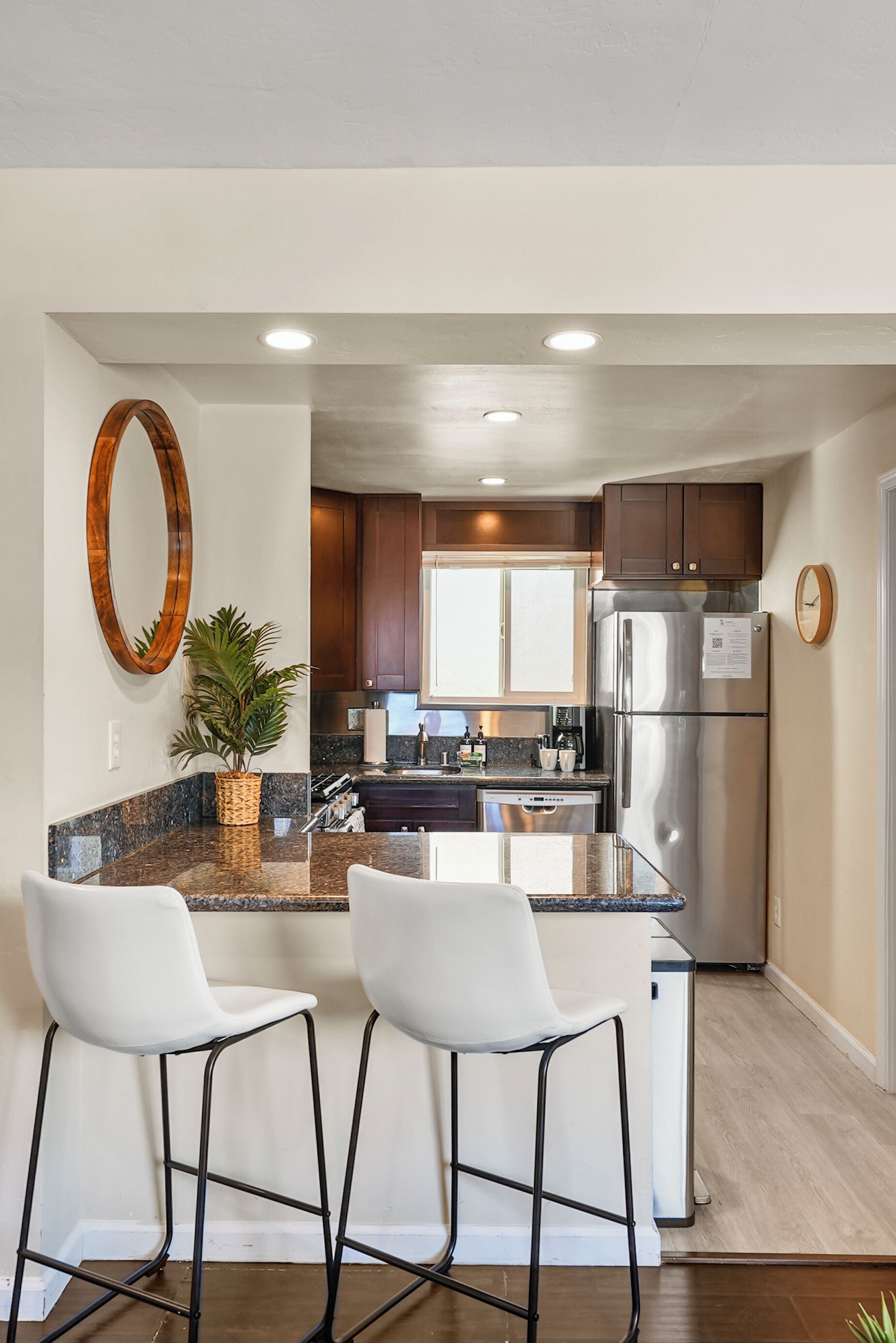 A modern kitchen with a central island, stainless steel appliances, and a large mirror.