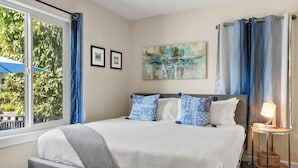 A bedroom with a bed, a ceiling fan, a window with curtains, and a painting on the wall. - Riviera Bay View Dream - Private Patio with Bay View, Parking & W/D! (San Diego)