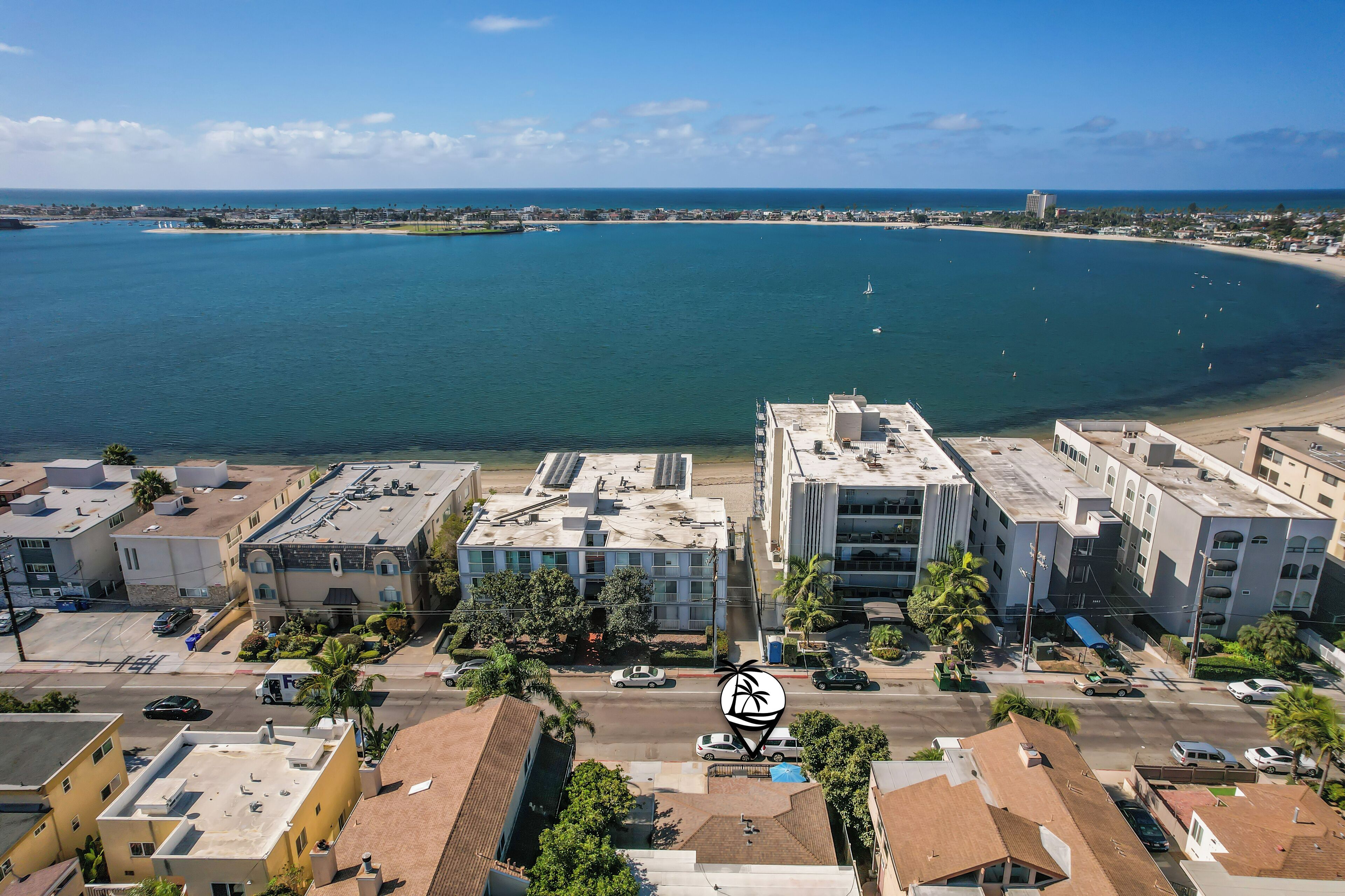 An aerial view of a coastal area with buildings, a beach, and a marina.
