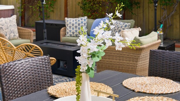 An outdoor patio with round woven placemats, a white vase with flowers, wicker furniture, and a dark-colored table. - La Jolla Dream! Amazing Location - Large Patio, Fire Pit and Parking! (La Jolla)