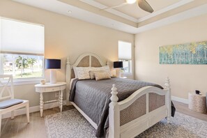 Une chambre à coucher avec un lit, des tables de chevet, une chaise, une fenêtre et un tableau au mur.