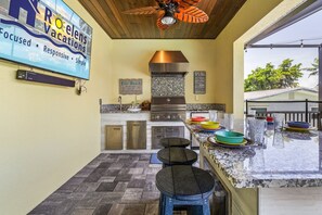 Une cuisine dotée d’un grand îlot central, d’appareils électroménagers en acier inoxydable et d’un ventilateur de plafond.
