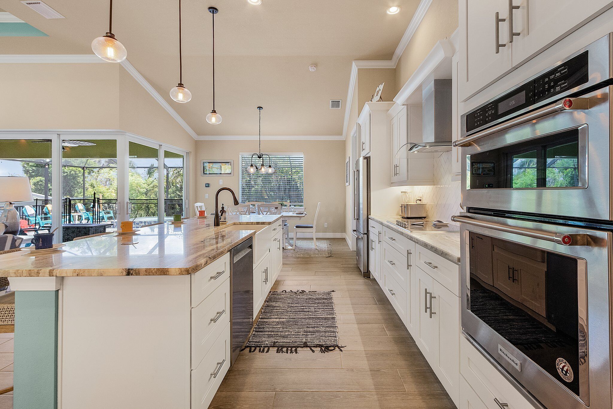 A modern kitchen with white cabinets, stainless steel appliances, and a large island with a built-in oven.