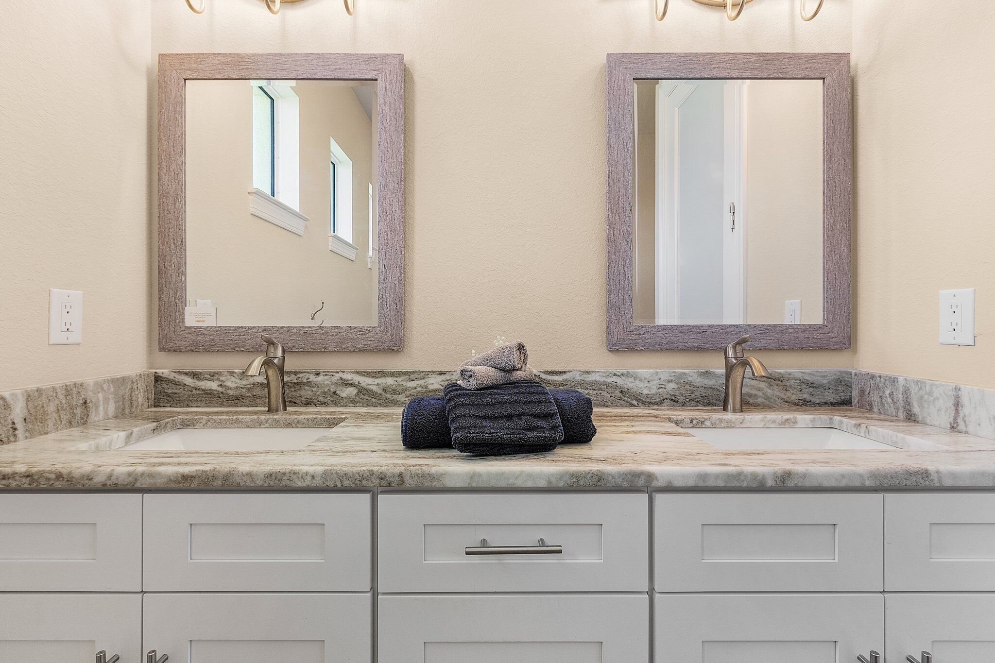 A bathroom with two sinks, marble countertops, and a mirror with a wooden frame.
