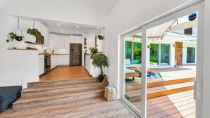 Een modern interieur met een houten trap die leidt naar een glazen deur naar een terras.