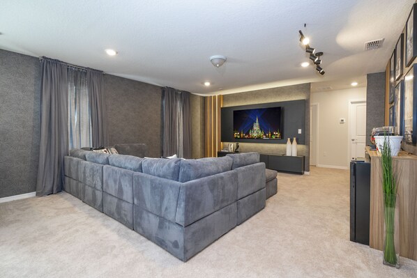 A modern living room with a sectional sofa, a flat-screen TV, and a minimalist decor.