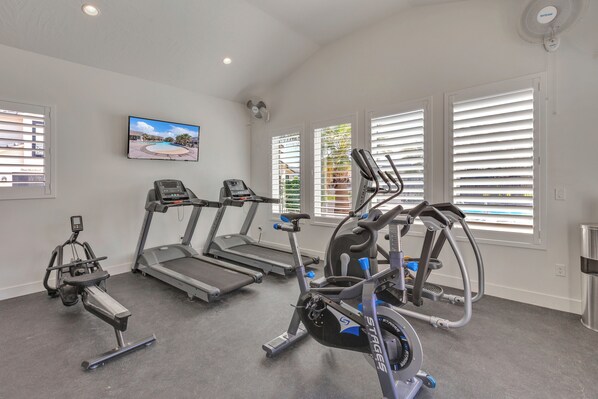 Un gimnasio con cintas de correr, elípticas y bicicletas estáticas.