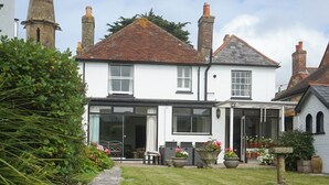 A two-story house with a stone pathway leading to the entrance, surrounded by a well-maintained garden with various plants and flowers. - Landguard - Yarmouth, Isle of Wight (Isle of Wight)