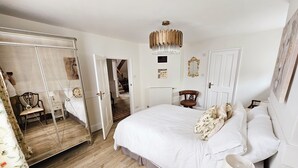 A bedroom with a large bed, a mirror, a chandelier, and a wooden floor. - Landguard - Yarmouth, Isle of Wight (Isle of Wight)
