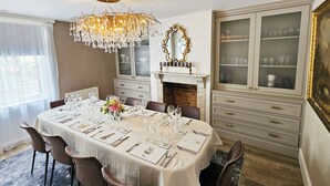A dining room with a chandelier, a fireplace, and a large cabinet with glass doors. - Landguard - Yarmouth, Isle of Wight (Isle of Wight)