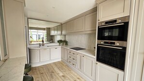 A kitchen with white cabinetry, a marble countertop, and a double oven. - Landguard - Yarmouth, Isle of Wight (Isle of Wight)