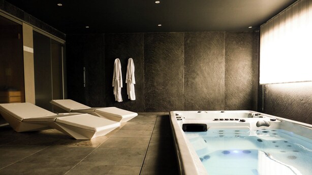 A modern bathroom with a large bathtub, two lounge chairs, and a towel rack. - Chalet Kusi Wasi is a luxury home in the heart of the pyrénées mountains  (Font-Romeu-Odeillo-Via)