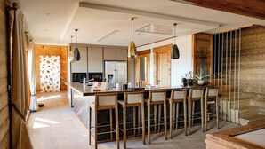 A modern kitchen with a central island, bar stools, and a pool table. - Chalet Kusi Wasi is a luxury home in the heart of the pyrénées mountains  (Font-Romeu-Odeillo-Via)