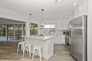 Una cocina moderna con una isla grande, electrodomésticos de acero inoxidable y vistas a una piscina.