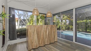Quarto moderno com grandes janelas, parede de destaque em madeira e piscina visível através do vidro.