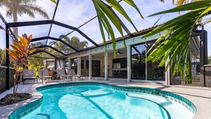 Piscina com cobertura de vidro, rodeada por espreguiçadeiras e um terraço coberto.