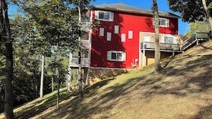 Een rood, twee verdiepingen tellend gebouw met een balkon, omgeven door bomen en een grashelling.