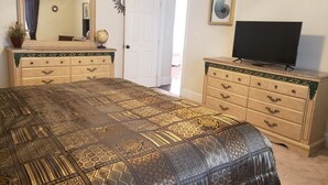Een slaapkamer met een groot bed, twee nachtkastjes, een televisie en een deur naar een buitenruimte.