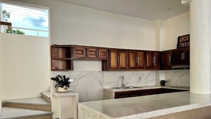 A modern kitchen with wooden cabinets, a marble backsplash, and a large island. - Casa Boutique Maria Bonita  (La Manzanilla)