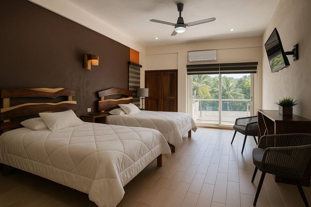 A hotel room with two queen beds, a desk, a chair, a ceiling fan, and a large window with a view of palm trees.