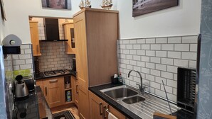 Uma cozinha compacta com armários de madeira, bancada preta e pia de aço inoxidável.