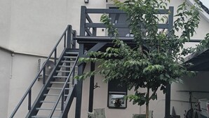 Un edificio con escaleras, mesas al aire libre y un árbol.
