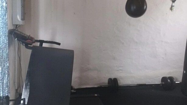 Una habitación con pared blanca, un saco de boxeo y una silla.