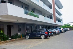 Stylish residential building with balconies and a clean architectural design, set amidst a landscaped area with parking.