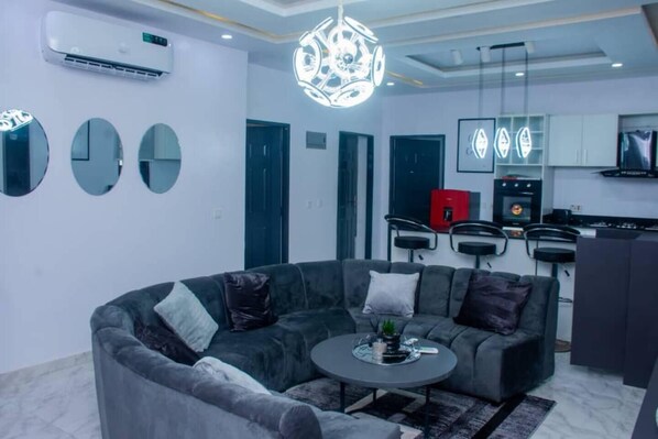 Relax in this stylish living space with a comfortable sofa, coffee table, and modern chandelier.