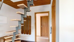 Una escalera de caracol con peldaños de madera y barandillas de metal, que conduce a una puerta.