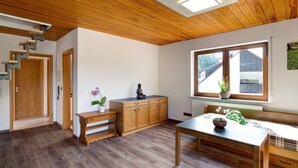 Una habitación con escalera de madera, un banco, una mesa y ventana con vistas.