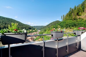 A balcony with potted plants and a view of a valley.
