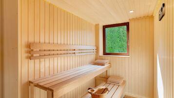 Un sauna avec des bancs en bois, une fenêtre et un seau en bois.